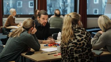 Kursdeltagare som sitter runt ett bord och diskuterar engagerat.